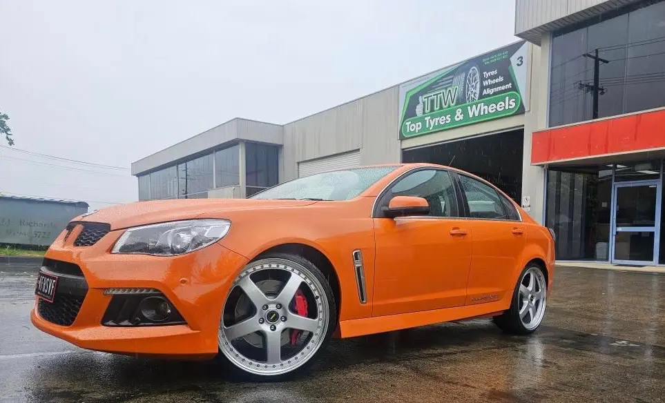 Orange performance sedan with fitted alloy wheels outside the workshop