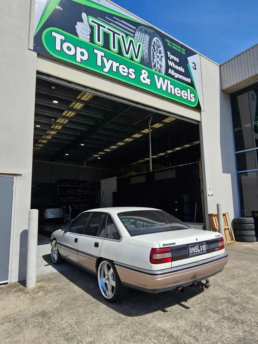 White sedan with fitted wheels outside the tyre workshop