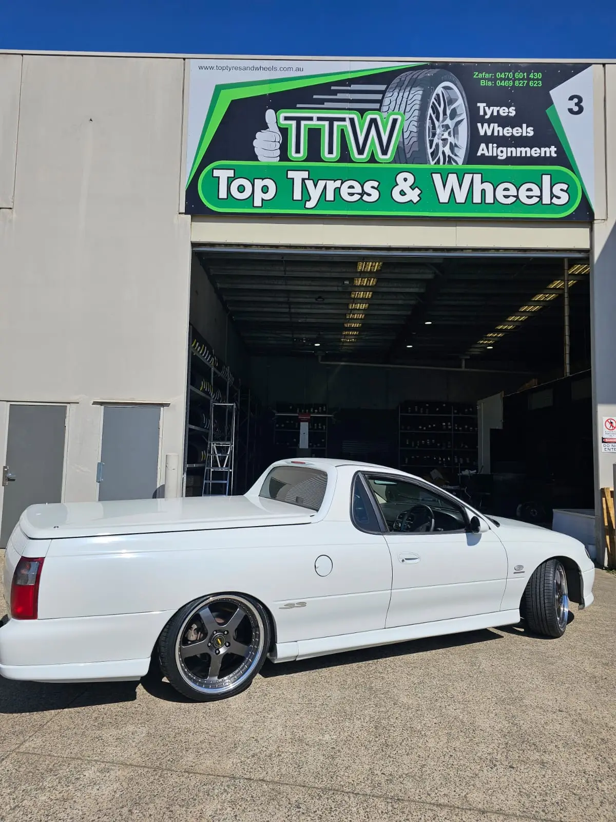 White ute with fitted deep-dish wheels outside the workshop